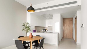 Eine moderne Küche mit weißen Schränken, einer zentralen Kochinsel und einem Essbereich mit Holztisch und schwarzen Stühlen.