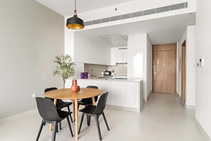 A modern kitchen with white cabinets, a central island, and a dining area with a wooden table and black chairs. - Silkhaus Canal Side 2bdr Apartment in Al Wasl (Dubai)