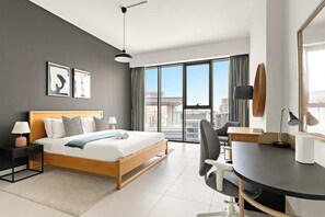 Ein modernes Hotelzimmer mit einem großen Bett, einem Schreibtisch und Blick auf die Stadt.
