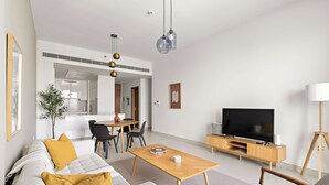 A modern living room with a sofa, coffee table, TV, and dining area. - Silkhaus Scenic Waterfront 2BR in Al Wasl (Dubai)