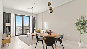 A modern living room with a dining area, large windows, and a view of the cityscape. - Silkhaus Scenic Waterfront 2BR in Al Wasl (Dubai)