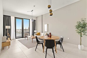 A modern living room with a dining area, large windows, and a view of the cityscape. - Silkhaus Scenic Waterfront 2BR in Al Wasl (Dubai)