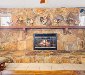 A stone fireplace with a glass door, surrounded by a stone wall. - 3BR Pool Home for 8 Easy Access to I-75 and I-4 (Valrico)