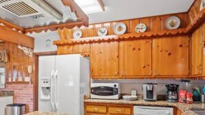 Uma cozinha com armários de madeira, geladeira branca, micro-ondas, cafeteira e lava-louças.