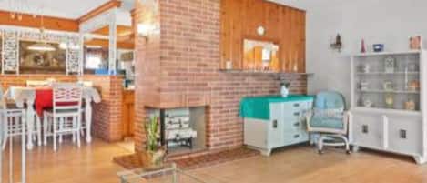 A living room with a fireplace, a dining area, and a kitchen area.