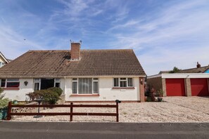 A residential house with a tiled roof, a chimney, and a red garage door. - 56 Steart Gardens (Burnham-on-Sea)