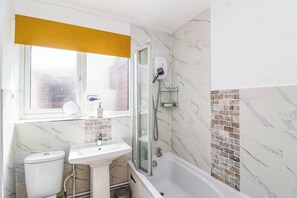 A bathroom with a toilet, sink, and shower. - 56 Steart Gardens (Burnham-on-Sea)