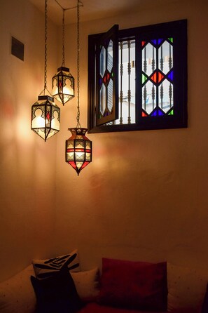 Una habitació amb un llit, una finestra amb vitralls i fanals penjants.