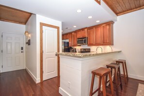 Una cocina con armarios de madera, encimera de granito y una isla integrada con taburetes.