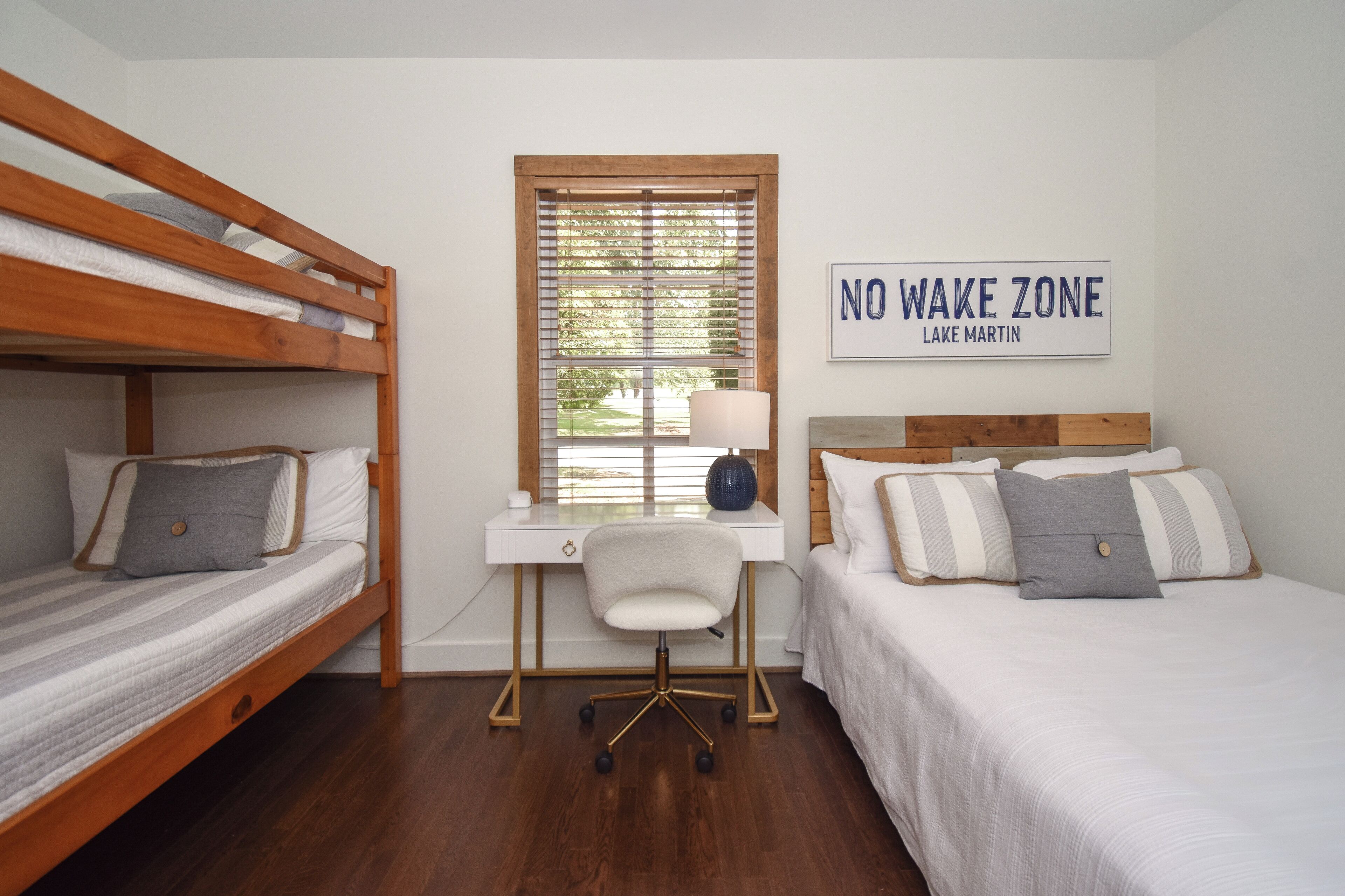 A bedroom with two bunk beds, a desk with a chair, and a 'NO WAKE ZONE' sign.