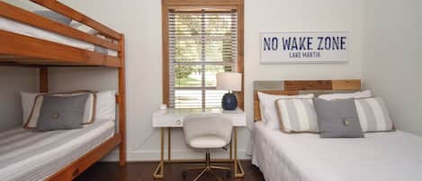 A bedroom with two bunk beds, a desk with a chair, and a 'NO WAKE ZONE' sign.