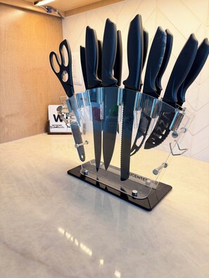 A kitchen counter with a knife block holding various knives.