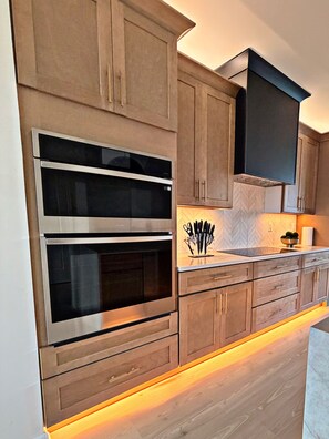 Una cocina moderna con electrodomésticos integrados, armarios de madera y un salpicadero con estampado en espiga.