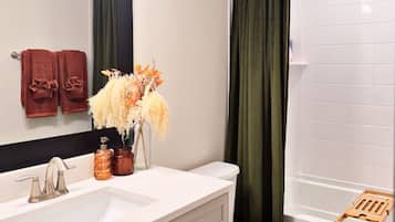 A bathroom with a white sink, a mirror, a toilet, and a shower curtain.