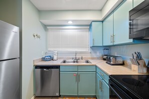 A kitchen with a stainless steel refrigerator, a dishwasher, a sink, a toaster, and a microwave. - Lei Lani Mini Tower 117N by Liquid Life (Orange Beach)