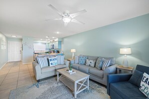 Ein Wohnzimmer mit Deckenventilator, einer Couch, einem Couchtisch und einer Lampe.
