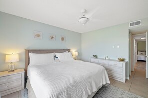 Ein Schlafzimmer mit einem Bett, Nachttischen, einem Deckenventilator und Wanddekorationen.