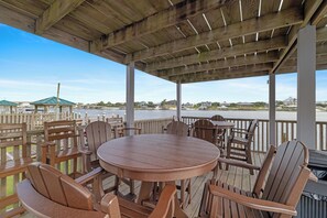 A covered outdoor seating area with wooden furniture and a view of the water. - Lei Lani Mini Tower 117N by Liquid Life (Orange Beach)