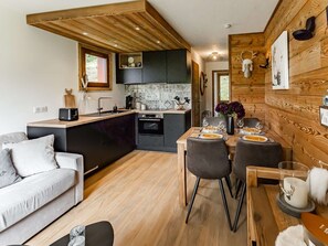 A modern kitchen with wooden accents, a dining area with a wooden table and chairs, and a cozy seating area with a sofa. - Renovated apartment at the foot of the slopes - 4 guests (Belle Plagne)