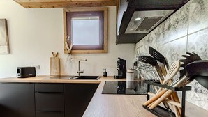 Una cucina moderna con un piano di lavoro nero, mobili in legno, una finestra e uno schienale.