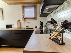 Eine moderne Küche mit schwarzem Arbeitsplatz, Holzschränken, einem Fenster und einer Spritzschutzwand.