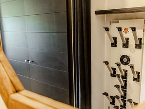 A room with a dark tiled wall, a wooden chair, and a white wall with a mechanical device. - Renovated apartment at the foot of the slopes - 4 guests (Belle Plagne)