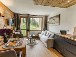A cozy room with a dining table set for two, a sofa, and a kitchen area with a toaster.