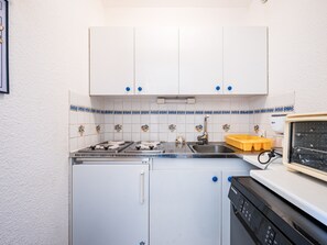 A kitchen with white cabinets, a stove, a sink, and a dishwasher. - Spacious apartment, slopes view - 7 guests (Le Corbier)