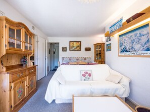 A cozy room with a white sofa, wooden cabinets, and a dining table. - Spacious apartment, slopes view - 7 guests (Le Corbier)