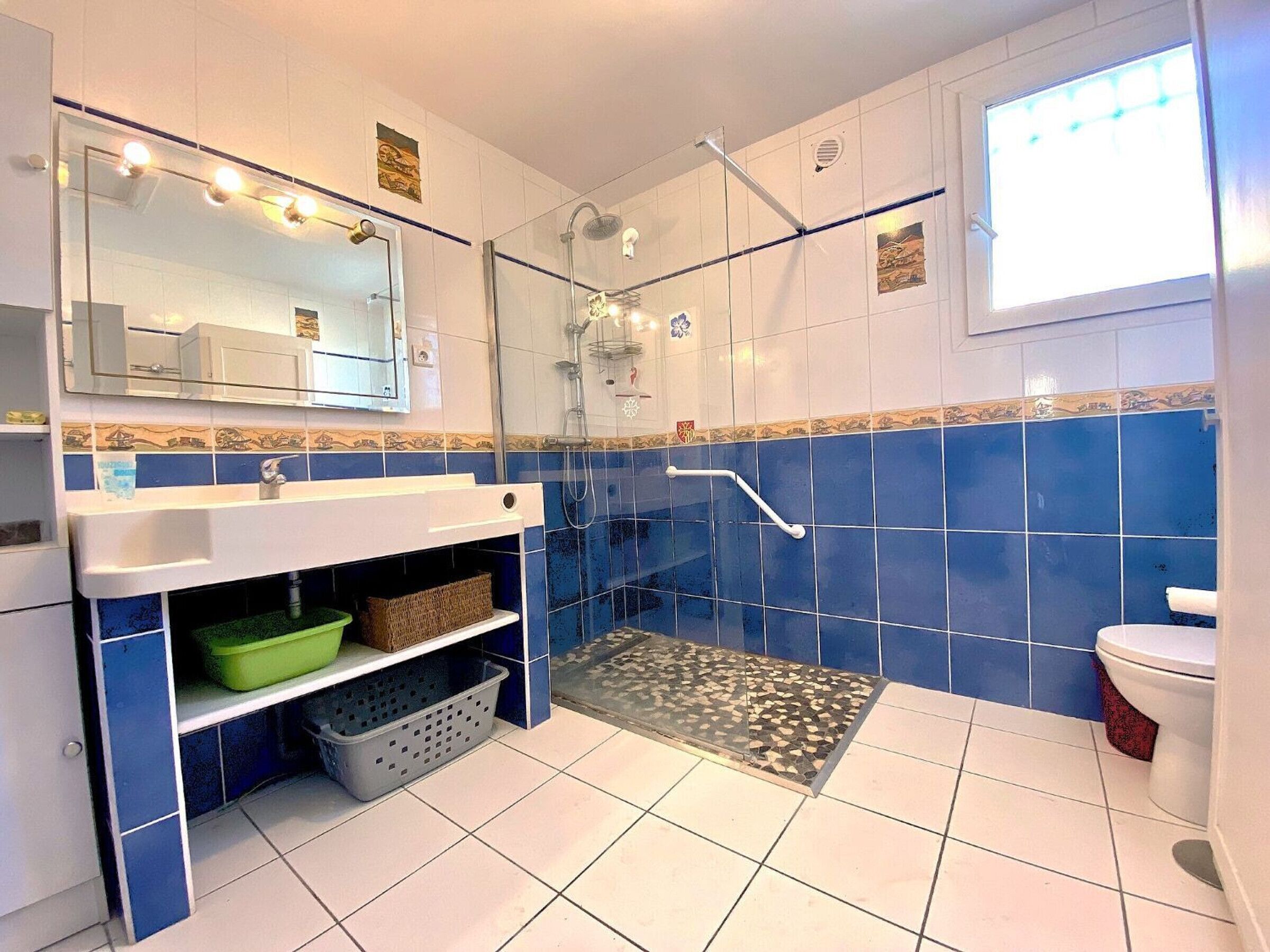 A bathroom with a glass-enclosed shower, a white sink, and a toilet.