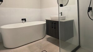 Ein modernes Badezimmer mit freistehender Badewanne, einer Duschkabine und einem Waschtisch mit Spiegel.
