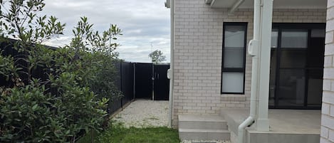 A modern house with a paved driveway, a small lawn, and a gravel pathway leading to the entrance.