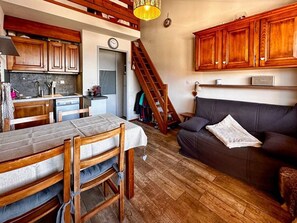 A cozy interior with a dining area, kitchen, and a staircase leading to an upper level. - Comfortable duplex studio - 4 guests (Crest-Voland)