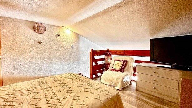 A bedroom with a bed, a dresser, a television, and a red-framed headboard. - Comfortable duplex studio - 4 guests (Crest-Voland)