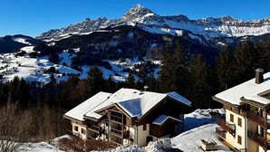 A mountain lodge with a view of snow-covered peaks, wooden architecture, and a clear sky. - Comfortable duplex studio - 4 guests (Crest-Voland)