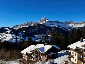 A mountain lodge with a view of snow-covered peaks, wooden architecture, and a clear sky. - Comfortable duplex studio - 4 guests (Crest-Voland)