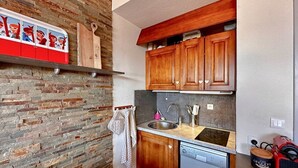 A compact kitchen with a dishwasher, wooden cabinets, a stone backsplash, and a hanging towel rack. - Comfortable duplex studio - 4 guests (Crest-Voland)