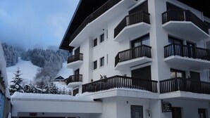 Um hotel com vários andares, varandas, garagem e uma placa indicando um restaurante.