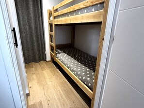 Una cama litera con colchón estampado, estructura de madera y pared gris.