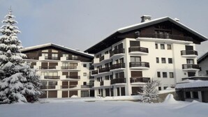 Um hotel de vários andares com varandas e paisagem coberta de neve.
