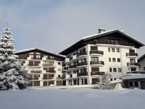 Ein mehrstöckiges Hotel mit Balkonen und verschneiter Landschaft.
