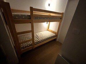 Ein Stockbett mit einer Matratze mit Herzmuster, einem Holzrahmen und einer an der Wand montierten Lampe.