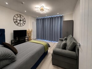 A modern bedroom with a bed, a sofa, a TV, and a wardrobe.
