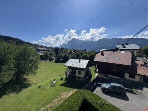 Ein Wohngebiet mit Häusern, einem Auto und Bergen im Hintergrund.