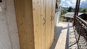 Eine Holztür mit Metallbeschlag, die auf einen Balkon mit Fliesenboden und schmiedeeisernem Geländer führt.