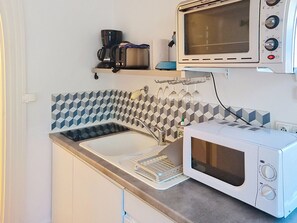 A compact kitchen with a microwave, a coffee maker, and a wine glass holder. - Apartment near the sea - 4 guests (Saint-Aubin-sur-Mer)