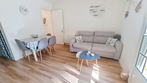 Ein Wohnzimmer mit einer Couch, einem Esstisch mit Stühlen und einem kleinen Couchtisch.