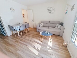 Ein Wohnzimmer mit einer Couch, einem Esstisch mit Stühlen und einem kleinen Couchtisch.