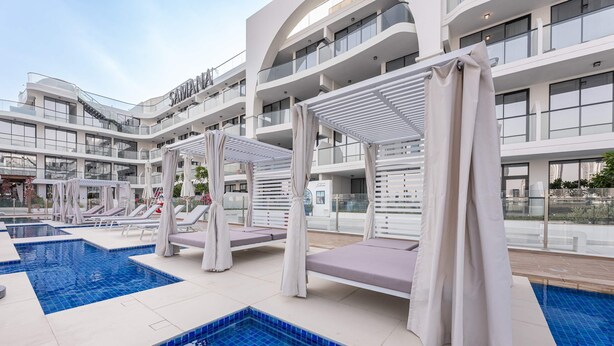 A modern hotel with a rooftop pool area, including lounge chairs and umbrellas. - Stayshort - Gorgeous Studio Apartment in Studio City Sleeps 4 With Balcony (Dubai)