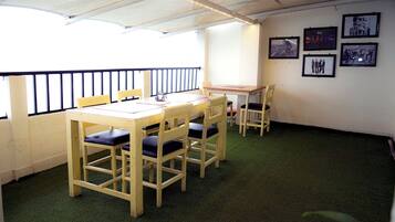 A room with a wooden table and chairs, a small table with a laptop, and framed pictures on the wall.